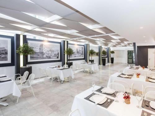罗德镇Mercure Rhodes Alexia Hotel & Spa的用餐室配有白色的桌子和白色的椅子
