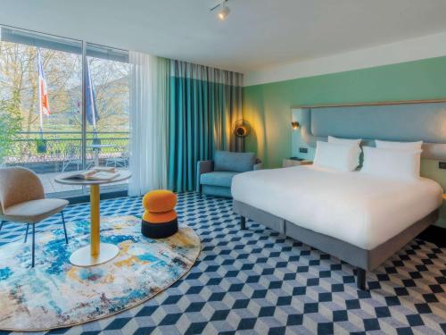 安锡Le Splendid Hotel Lac D'Annecy - Handwritten Collection的配有床、椅子和桌子的酒店客房