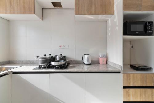 拉各斯Firenze Apartments Lekki的厨房配有白色橱柜以及带锅碗瓢盆的炉灶。