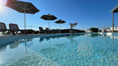 莫诺利索斯Hermoso Luxury Suites的一个带椅子和遮阳伞的游泳池