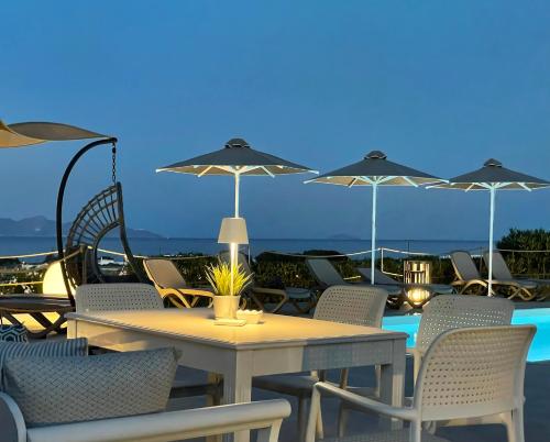 莫诺利索斯Hermoso Luxury Suites的庭院内桌椅和遮阳伞