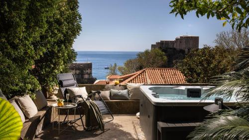 杜布罗夫尼克Dubrovnik Old Town Apartments的庭院设有热水浴池、桌子和椅子。