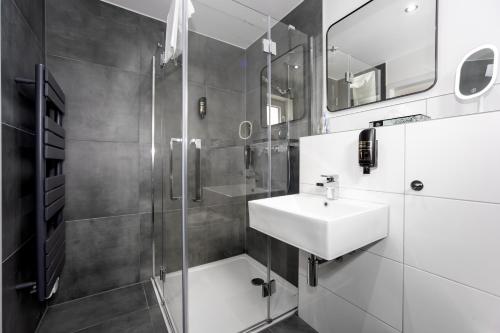 多斯滕Hotel Deluxe的白色的浴室设有水槽和淋浴。