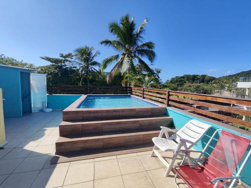 瓜鲁雅Pousada Sereia Tropical的庭院中设有一座带楼梯和两把椅子的游泳池