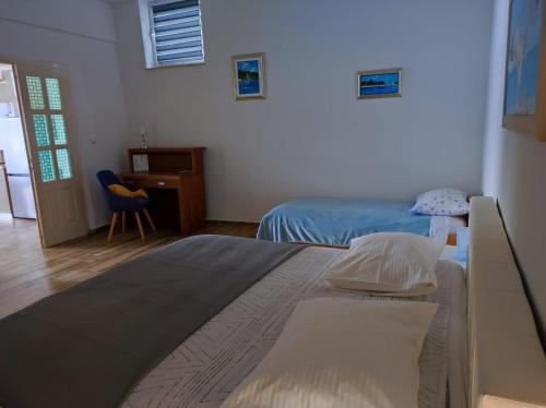 维甘Apartment Mareta in Viganj的一间卧室配有两张床、一张桌子和一把椅子