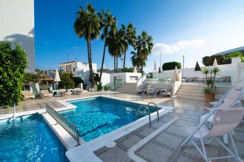 圣安东尼奥Hotel Tarba的一座带椅子和棕榈树的游泳池