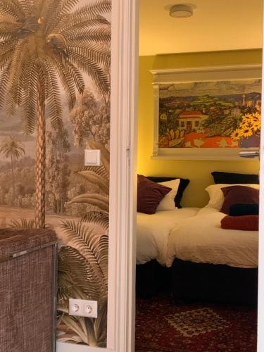 Den HamGanzenmars prive sauna, wellness tub and gamesroom的一间卧室设有两张床和棕榈树壁画