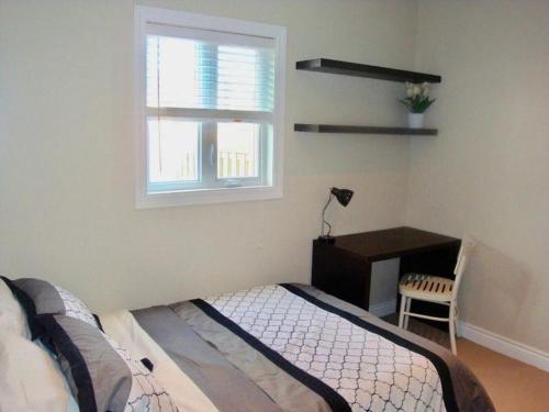 金斯顿Comfortable apartment的一间卧室配有一张床、一张书桌和一个窗户。