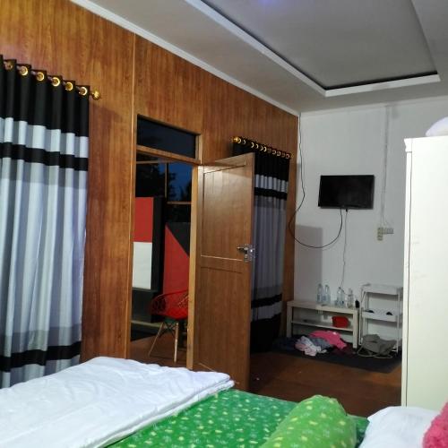 特尔纳特岛Ayu Park的一间卧室配有一张床,另一间配有电视。