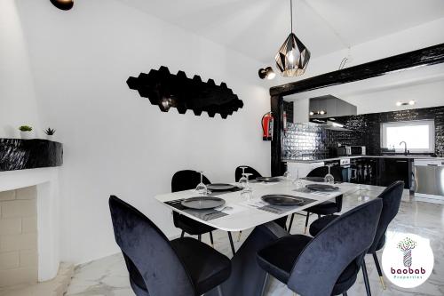 阿尔布费拉Villa Bellagio的一间配备有白色桌子和黑色椅子的用餐室