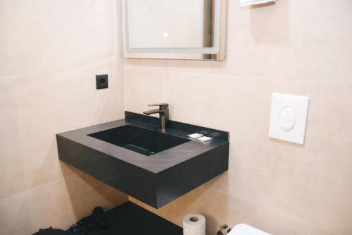 SuharekëHotel Rozafa的浴室设有黑色水槽和镜子