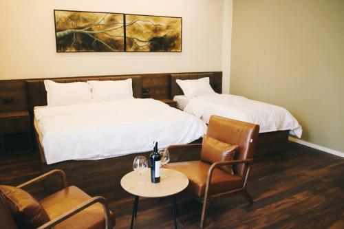 SuharekëHotel Rozafa的酒店客房带两张床和一张桌子以及椅子。