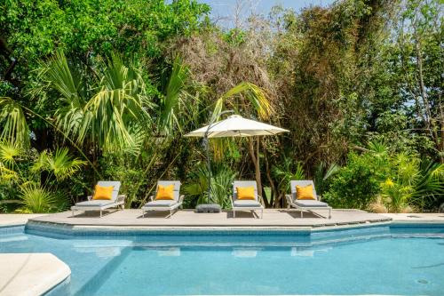 阿文图拉斯港Casa Manglar Riviera Maya的一组椅子和一把遮阳伞,位于游泳池旁