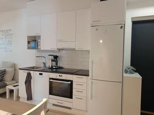 约恩苏Uusi kaksio parvekkeella ja autopaikalla的厨房配有白色橱柜和白色冰箱。