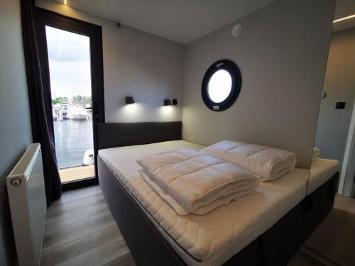 ÖsterhaningeHusbåt的一间卧室配有一张带白色床单的床和一扇窗户。