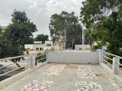 努瓦克肖特Auberge-Cafe Tunisie的白色的栅栏和有树木和建筑物的走道