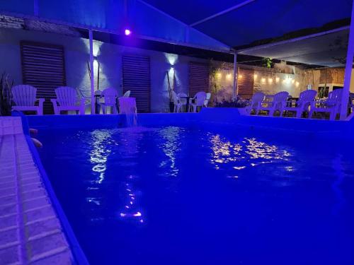 特尔马斯德里奥翁多Hotel Australia的夜间游泳池,配有白色的椅子和桌子