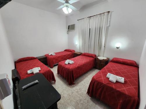 特尔马斯德里奥翁多Hotel Australia的红色床单的客房内的三张床