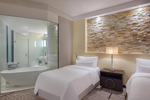 麦纳麦巴林威斯汀市中心酒店的一间酒店客房 - 带一张床、一个浴缸和一张床及一张床