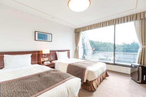 御殿场市富士御殿场伦勃朗高级酒店(Rembrandt Premium Fuji Gotenba)的配有大窗户的酒店客房内的两张床