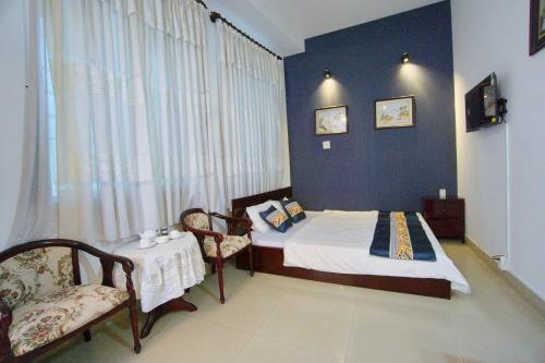Ấp Phước ThọHotel Hải Châu的卧室配有一张床和一张桌子及椅子