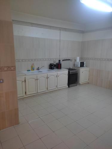 Le BardoAppart Cozy的厨房配有白色橱柜和白色瓷砖地板。
