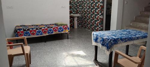 克久拉霍happy khajuraho home stay的一间设有两张床和一张桌子及椅子的房间