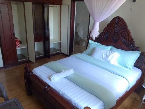 恩德培DISCOVERY COURTS HOTEL的一间卧室配有一张大床和木制床头板