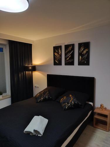 雷瓦Villa Port的卧室配有一张黑色床,墙上挂有三张照片