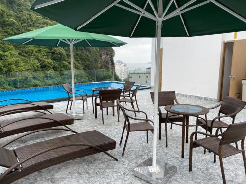 吉婆岛Sand Hotel的一组桌椅,在游泳池旁边配有遮阳伞