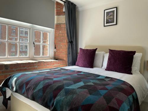 约克Staycation York at Cocoa Suites的一间卧室配有一张带紫色枕头的床和窗户。
