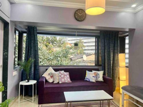 孟买Newton Villa, A Hidden Gem with a Pvt Terrace in the Heart of Bandra by Connekt Homes的客厅配有紫色沙发和窗户