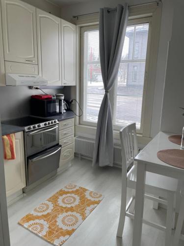 许温凯Yksiö+autopaikka/Small apt.+free parking的厨房配有白色橱柜、桌子和窗户。