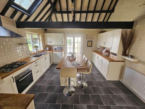 吉尔福德English Farmhouse Cottage的厨房配有白色橱柜和木桌