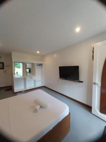 CamisanLoboc Nipa Huts Cottages Rental的卧室配有一张白色大床和一台平面电视。