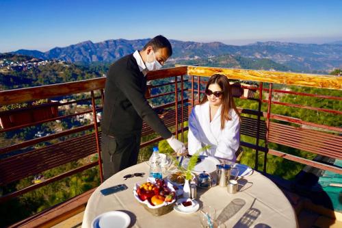 柴尔Nature View Resort !! A Four Star Lavish & Luxury Resort的男人和女人站在餐桌上吃饭