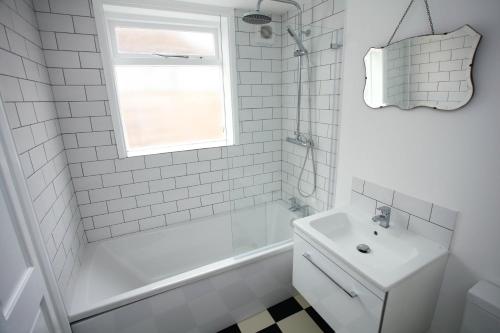 KentBarnacle Drift - a stylish Whitstable cottage的白色的浴室设有浴缸和水槽。