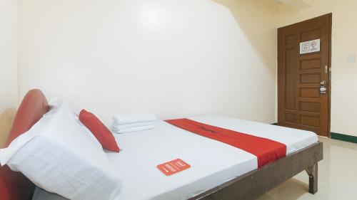 马尼拉RedDoorz @ Western Bicutan Transients Inn的一间卧室配有带白色床单和红色枕头的床。