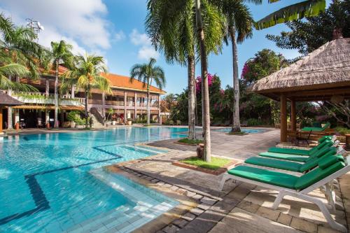 努沙杜瓦普拉戈假日酒店 的度假村的游泳池,设有躺椅和棕榈树