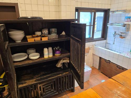 龙潭OLD WOW老屋瓦共享民宿Hostel 桃園市民宿074號的厨房配有带盘子和碗的架子