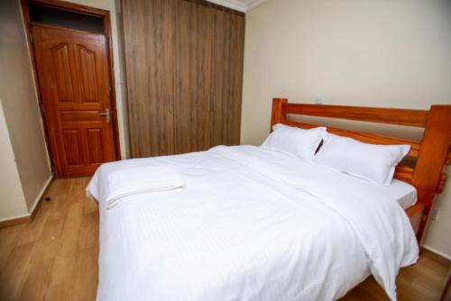 MeruWHITE LOTUS EXECUTIVE APARTMENT的卧室配有一张白色大床和木制床头板