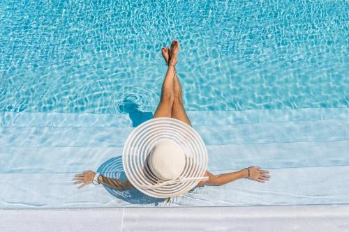 斯泰里达Naxos Cave Suites的戴着帽子的女人躺在游泳池里