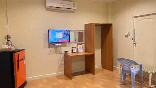 Ban Na Oiที่พักสกลนครกรีนเฮ้าส์รีสอร์ท的配有电视、桌子和椅子的房间