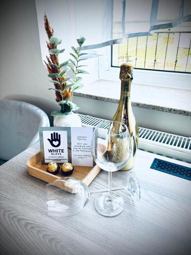 弗瓦迪斯瓦沃沃Willa Aleksandra White Glove的一张桌子,上面放着一瓶葡萄酒和一杯