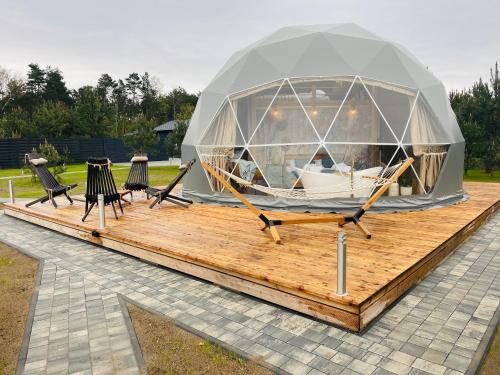 DzbądzekIdyllaGlamp- Glamping Boho的木制甲板上的大型帐篷,配有椅子