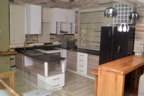 坎帕拉Isabirye residence的厨房配有白色橱柜和黑色冰箱。