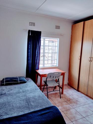 卢萨卡bliss stay的一间卧室配有一张床、一张书桌和一个窗户。