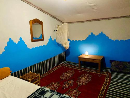 姆哈米德Auberge L'oasis Mhamid的一间设有一张桌子和一张床的蓝色墙壁客房