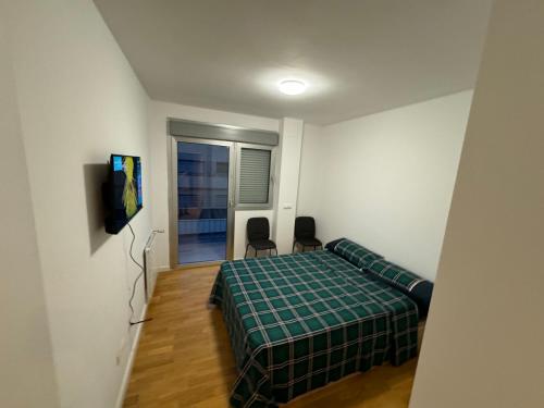 马德里Hotelly Recuero的一间卧室配有一张床、两把椅子和电视