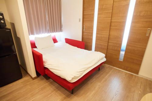 东京SG Premium KASAI - Vacation STAY 44353v的一张小床,位于一个红色椅子的房间